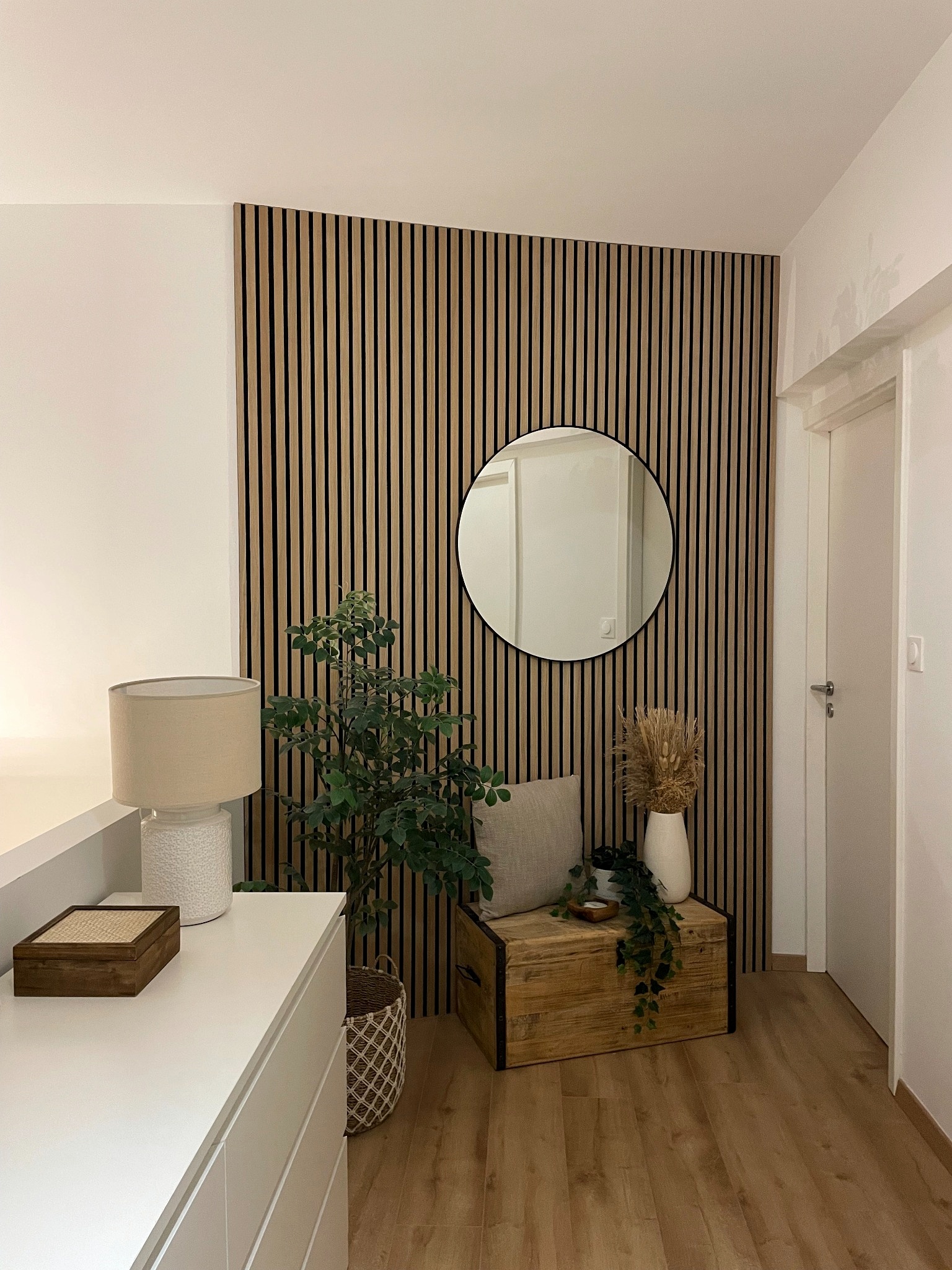Vue d’ensemble du mur habillé de tasseaux avec miroir rond