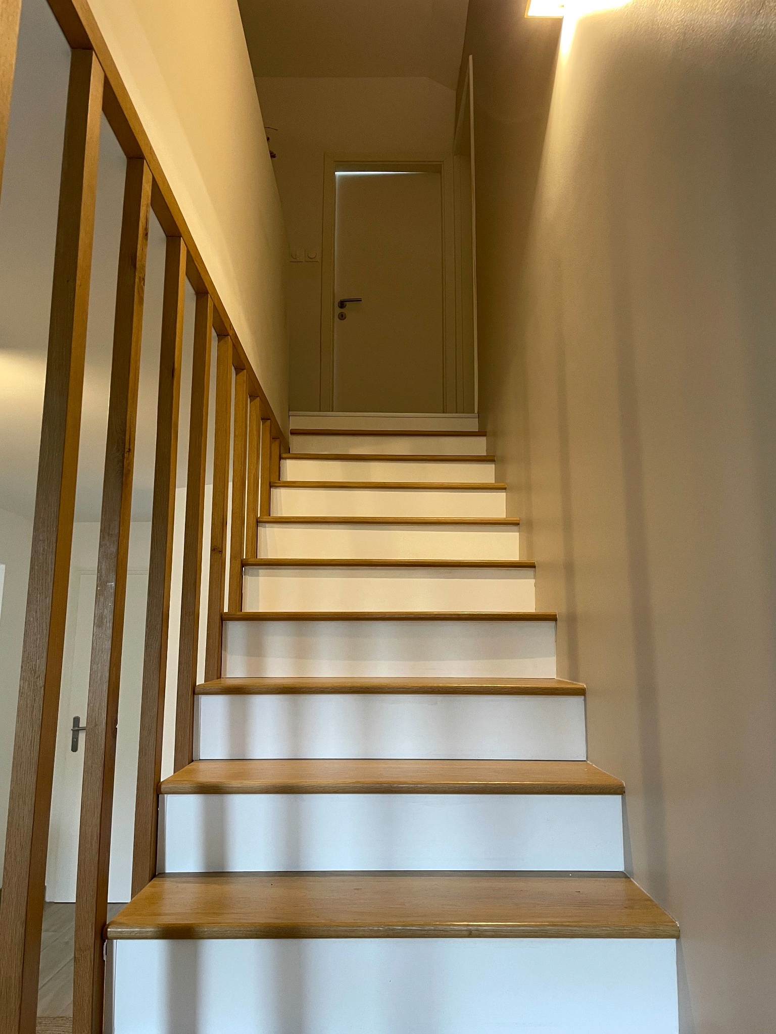 Escalier rénové avec marches en bois, contremarches blanches et garde-corps